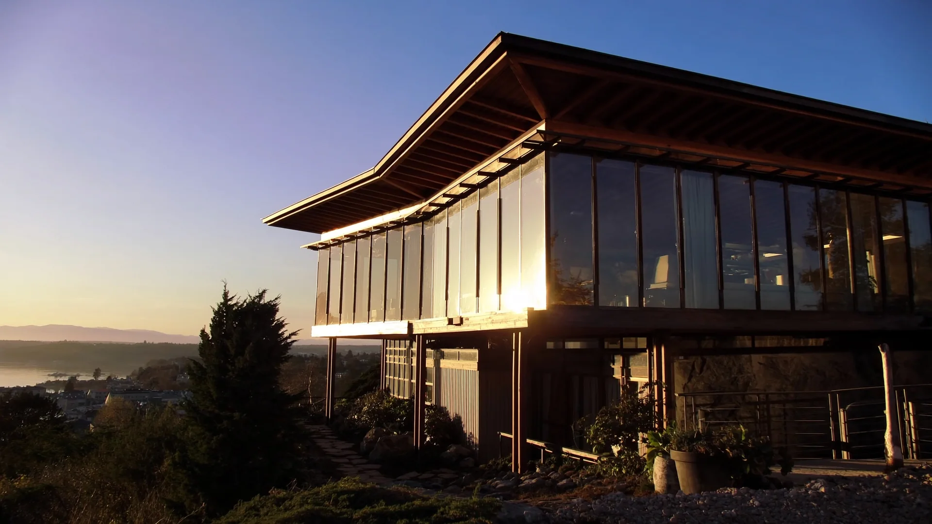Two-story glass pavilion home at golden hour